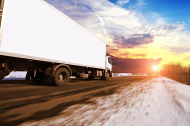 Yazmak için yeri olan beyaz bir kamyonet kırsal kış yolunda hızla giderken gün batımına karşı gökyüzü karla kaplıydı.