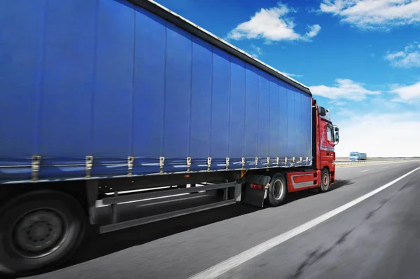 大きな赤いトラックと雲と青空に対する田舎道で高速運転テキストのためのスペースを持つ青いトレーラー — ストック写真