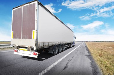 Kırsal yolda bulutlu mavi gökyüzüne karşı yazı için yeri olan büyük bir kamyon ve karavan.