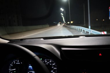 Arabalar ve lamba direkleriyle karanlık ve bulanık gece yolu.