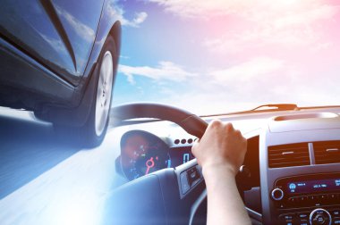 Siyah arabanın yakın planına sahip soyut arka plan, mavi ve turuncu ışıklarla gökyüzüne karşı direksiyon simidi