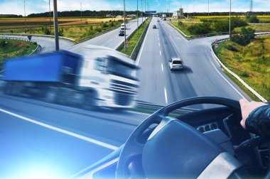 Kamyon hareket halindeyken soyut arka plan, direksiyon simidi ve yolu arabalar ve mavi ışıklı mavi gökyüzü.