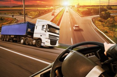 Kamyon, kamyon direksiyonu, yol, arabalar ve gün batımlı gökyüzü soyut arkaplan