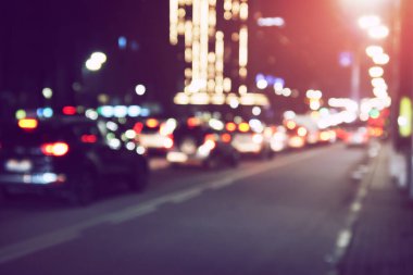 Karanlık gece sokak arabalarının, trafiğin ve klasik filtresi olan ışıkların odaksız görüntüsü