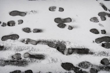 Beyaz karda siyah ayakkabı izleri. 