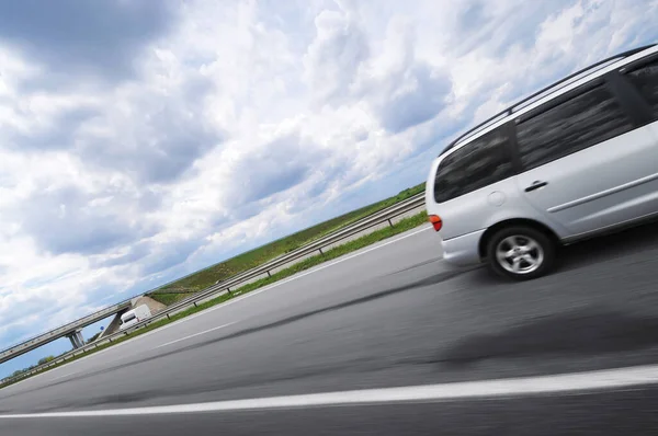 Srebrny Minivan Jadący Szybko Wiejskiej Asfaltowej Drodze Przed Zachmurzonym Niebem — Zdjęcie stockowe