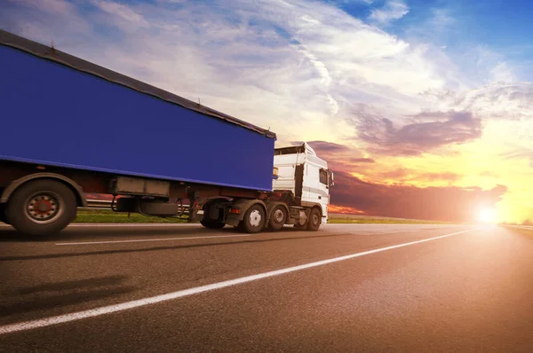 大きな白いトラックと日没と空に対する田舎道のテキストのためのスペースを持つ青いトレーラー — ストック写真