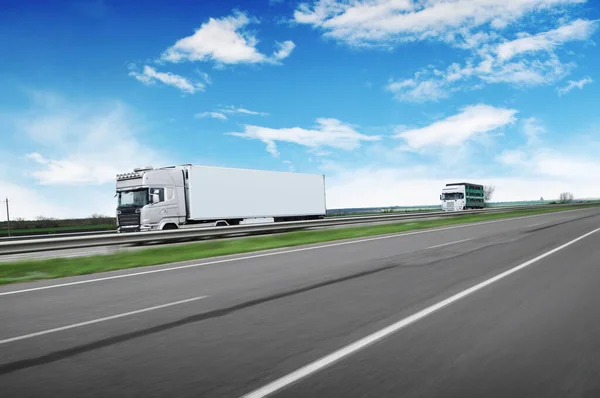 テキストや雲と青空に向かって田舎道で高速運転他のトラックのためのスペースを持つ大きなトラックや白いトレーラー — ストック写真