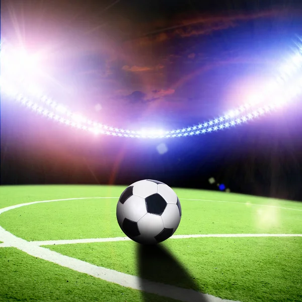 明るい照明と夜に点滅するスタジアムで運動中のボールと緑のサッカー場の中心 — ストック写真