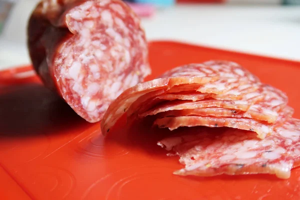 Primo Piano Della Salsiccia Salame Affettata Sul Tagliere Plastica Rossa — Foto Stock