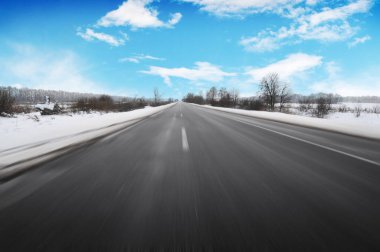 Boş kış kırsal yol hareket ağaçlar ve mavi gökyüzü bulutlu karşı beyaz kar
