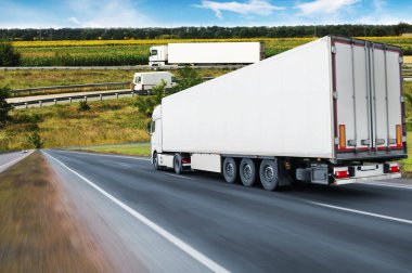 Römorklu kamyonlarla soyut arkaplan ve mavi gökyüzüne karşı tarlalı yol