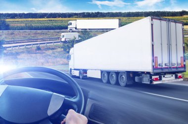 Römorklu kamyonlarla soyut bir arkaplan, direksiyon simidi ve yol mavi gökyüzüne karşı ışıklandırmalı.