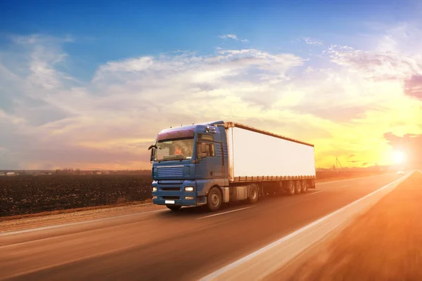 大きな青いトラックと日没と空に対して運動中の田舎道上のテキストのためのスペースを持つ白いトレーラー — ストック写真