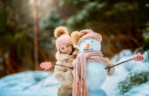 Kleines Mädchen mit Schneemann — Stockfoto
