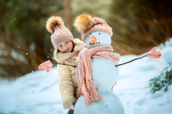 Маленькая девочка со снеговиком — стоковое фото