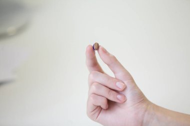 Bir kadının elinde çok küçük bir işitme cihazı