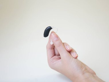 Bir kadının elinde çok küçük bir işitme cihazı