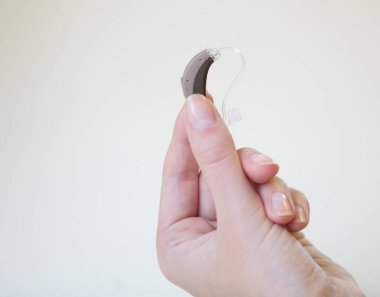 Bir kadının elinde çok küçük bir işitme cihazı