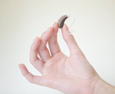 Kadınların elindeki işitme cihazı çok küçük.