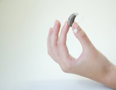 Bir kadının elinde çok küçük bir işitme cihazı