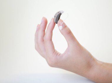 Bir kadının elinde çok küçük bir işitme cihazı