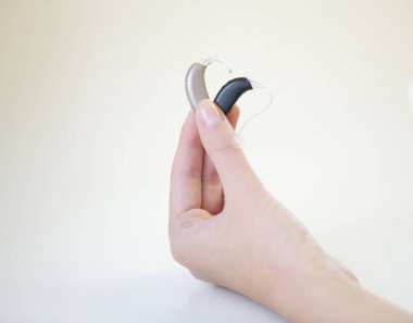 Bir kadının elinde iki farklı işitme cihazı.