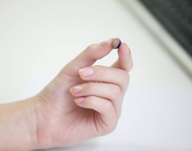 Bir kadının elinde çok küçük bir işitme cihazı