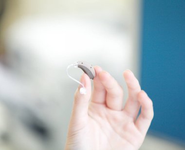 Bir kadının elinde çok küçük bir işitme cihazı