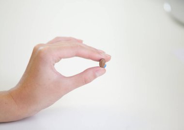 Bir kadının elinde çok küçük bir işitme cihazı