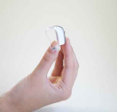 Bir kadının elinde çok küçük bir işitme cihazı