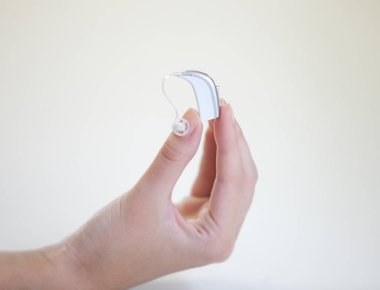 Bir kadının elinde çok küçük bir işitme cihazı