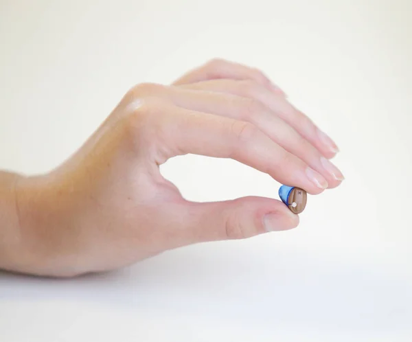 Bir Kadının Elinde Çok Küçük Bir Işitme Cihazı — Stok fotoğraf