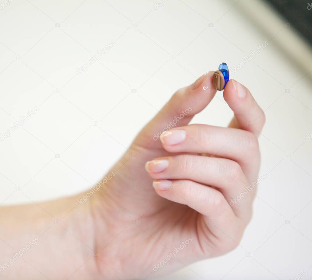 Very small hearing aid in a female hand