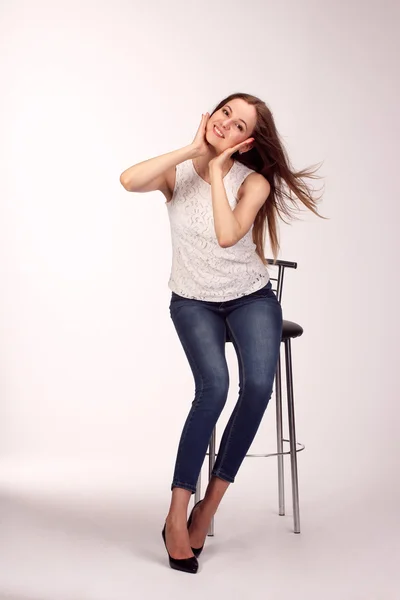 스튜디오에서 흰색의 자에 앉아 하나의 행복 한 젊은 여자 — 스톡 사진