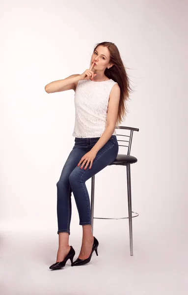 Mujer joven feliz sola sentada en una silla blanca en el estudio —  Fotos de Stock