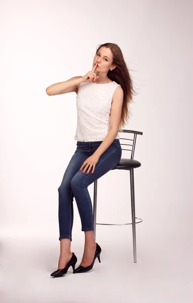 Single happy young woman sitting on a white chair in studio — Stock Photo, Image