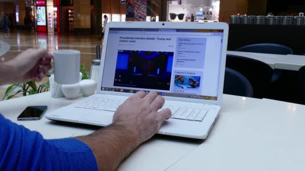 Hombre en el centro comercial leyendo noticias de la BBC en el portátil — Vídeo de stock