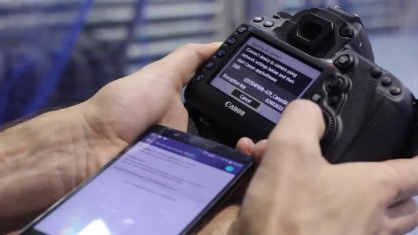 O homem estabelece uma conexão entre seu smartphone e a nova câmera SLR — Vídeo de Stock