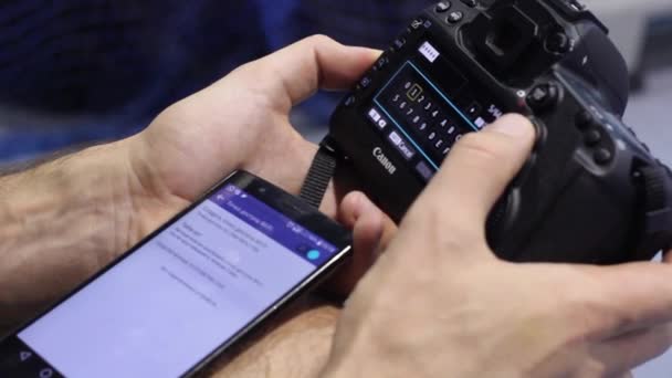 Человек устанавливает связь между вашим смартфоном и новой камерой SLR — стоковое видео