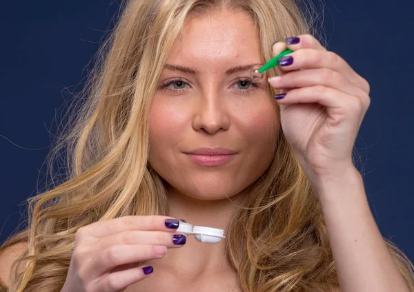Kvinna håller en kontaktlins med pincett — Stockfoto