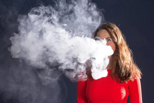 Mujer Fumando un cigarrillo electrónico sobre fondo azul — Foto de Stock