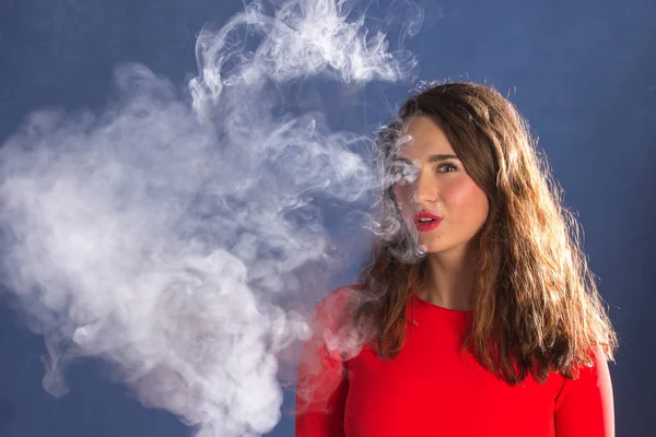 Femme Fumer une cigarette électronique sur fond bleu — Photo