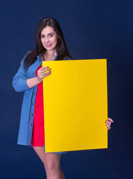 Ευτυχισμένη γυναίκα κρατώντας ένα κίτρινο κενό φύλλο χαρτιού — Φωτογραφία Αρχείου