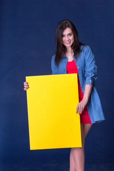 Mujer feliz sosteniendo una hoja de papel en blanco amarillo —  Fotos de Stock