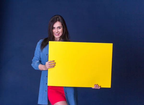 Šťastná žena držící žluté prázdný list papíru, na modrém podkladu — Stock fotografie