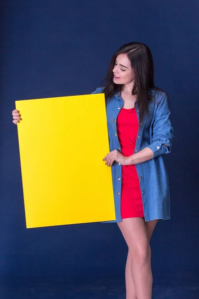 Mulher feliz segurando uma folha de papel em branco amarelo — Fotografia de Stock