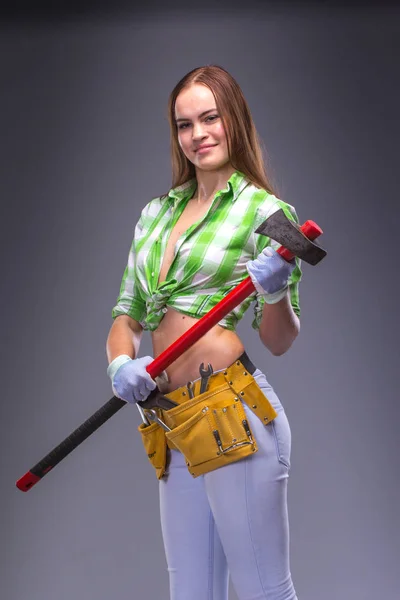 Female worker in overalls holding an axe — Stock Photo, Image