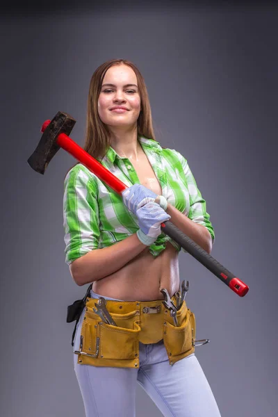 Female worker in overalls holding an axe — Stock Photo, Image