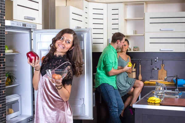 Kvinna som tittar till kylskåp med par på bakgrund. — Stockfoto